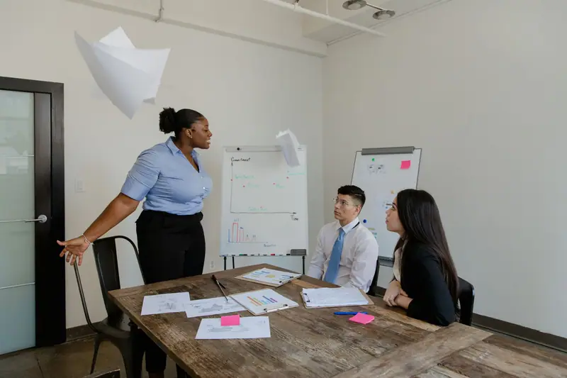 Team meeting around a table while a colleague presents at a flip chart
